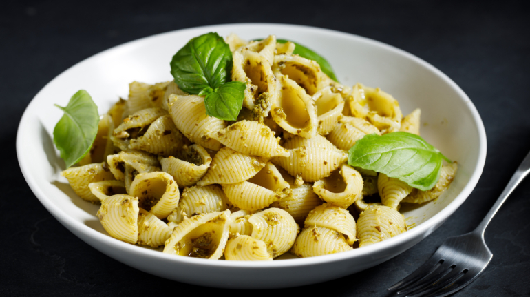 Conchiglie pasta with pesto sauce on dark background, vegan dish